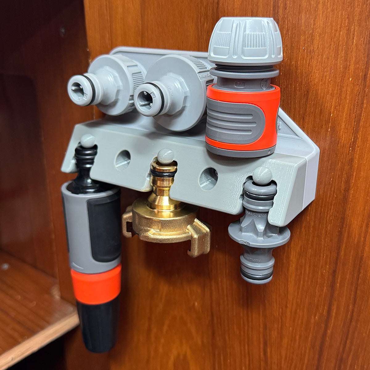 Hose accessory holder mounted on wall, fully loaded with quick-connect couplings and tap adapters